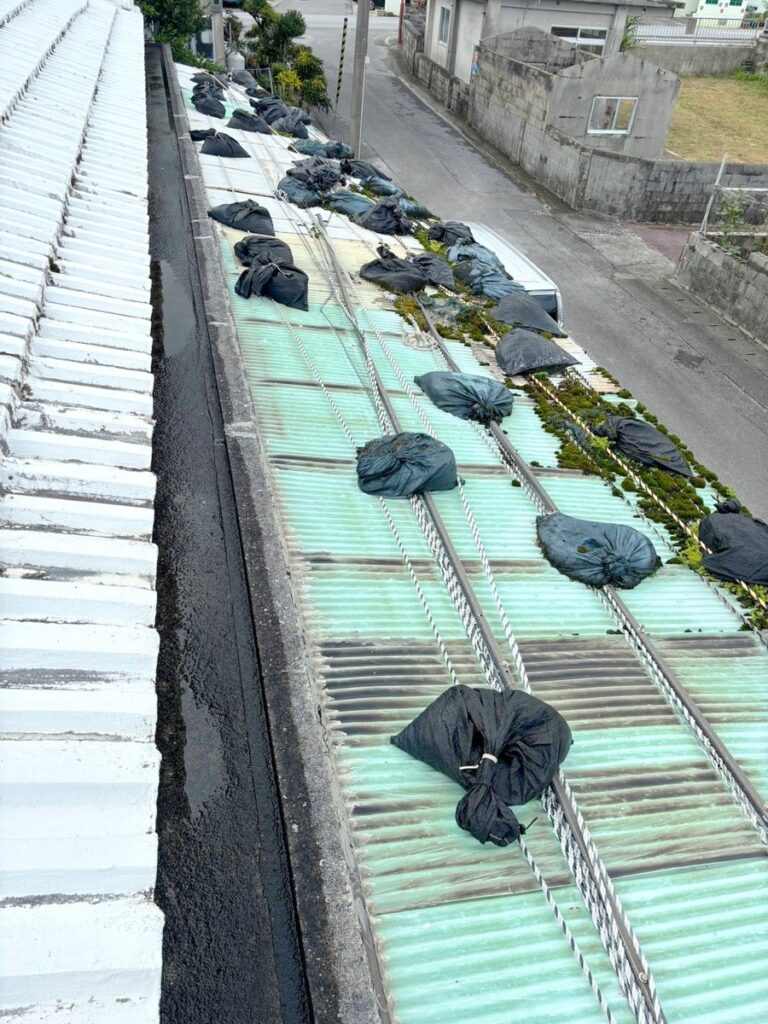 宜野座村 テラス屋根 波板張り替え 施工前 土のうで押さえた緑の波板